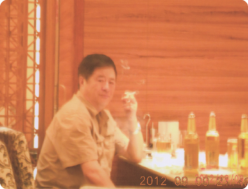 哈爾濱市東方餃子店で屈強な男性がたばこを吸いながらビールを片手ににらむ